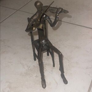 Brutalist-style cast metal sculpture of a seated violinist